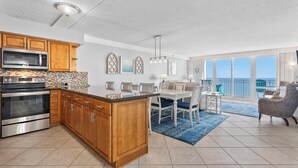A modern kitchen with wooden cabinets, stainless steel appliances, and a large island. - Oceanfront Carousel Condo • Beach Access Resort (Ocean City)