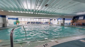 An indoor swimming pool with clear water, a 3 FT depth marking, and a view of the outside through large windows. - Oceanfront Carousel Condo • Beach Access Resort (Ocean City)