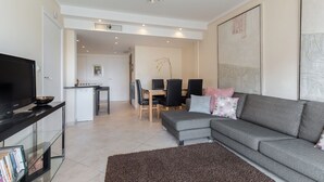 Una sala moderna con un sofá gris, un televisor de pantalla plana y una mesa de centro de cristal.