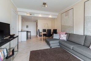 A modern living room with a grey sofa, a flat-screen TV, and a glass coffee table. - 3-bedroom apartment in awesome Cannes with cool AC breeze (Cannes)