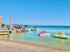 Ein Kiesstrand mit Booten an einem Steg.