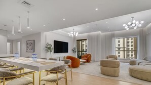 A spacious living room with a large dining table, comfortable seating, and a TV. - Sadaf 2701 (Dubai)