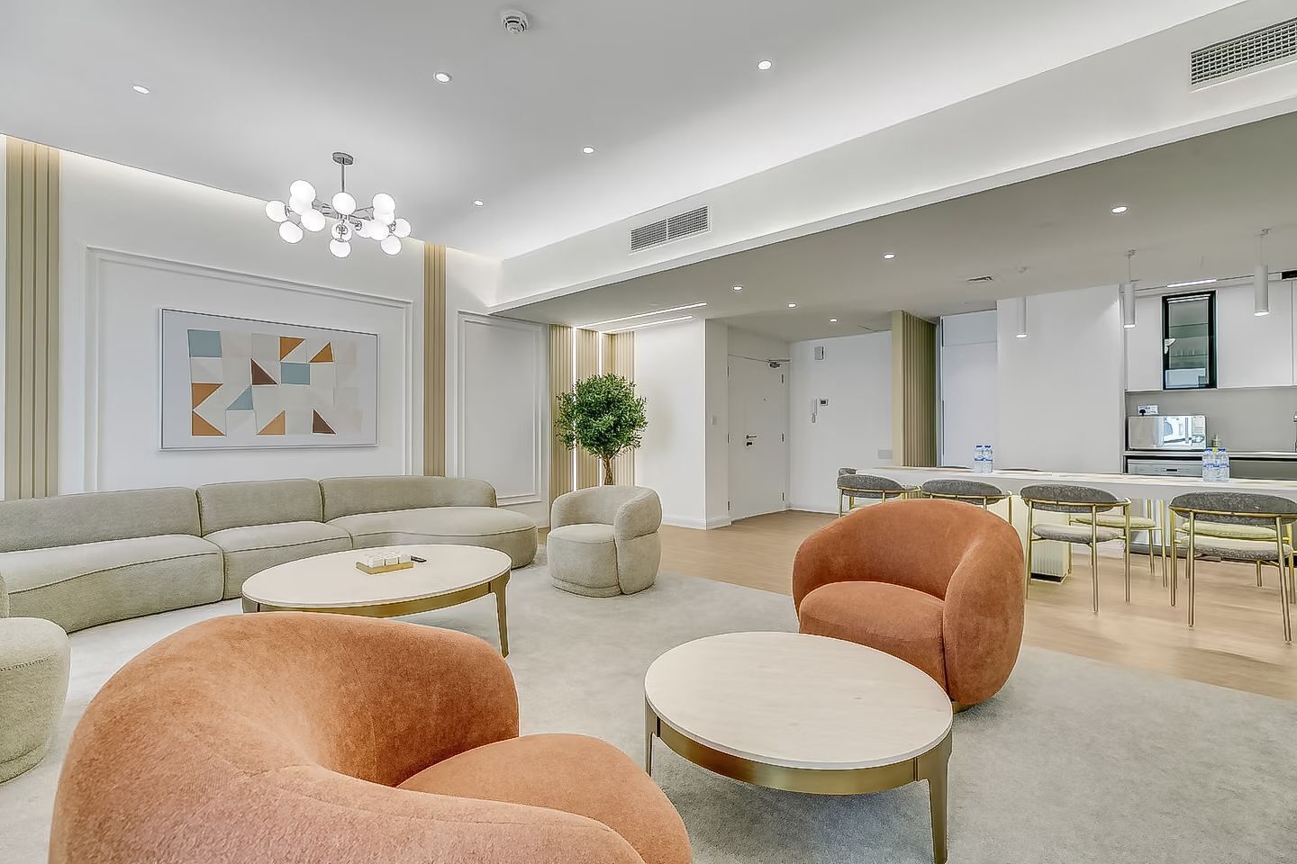 A modern living room with a sofa, armchairs, and a dining area with chairs and a table.