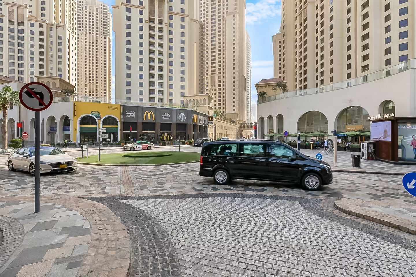 Una calle urbana con edificios altos, un McDonald's y un paso de peatones.