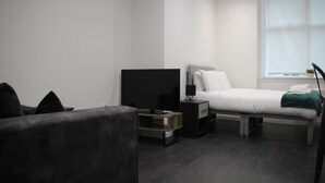Ein modernes Hotelzimmer mit einem Bett, einem Fernseher, einem Nachttisch und einem Fenster.