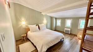 Ett sovrum med en stor säng, två sänglampor, ett trägolv och ett fönster.