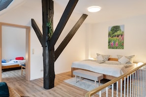 Un dormitorio con una cama grande, un tronco de árbol de madera, un banco y un cuadro de flores en la pared.