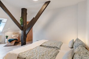A bedroom with a loft bed, a large wooden beam, and a potted plant. - Apartment 'Frieseneck' with Private Garden and Wi-Fi (Zetel)