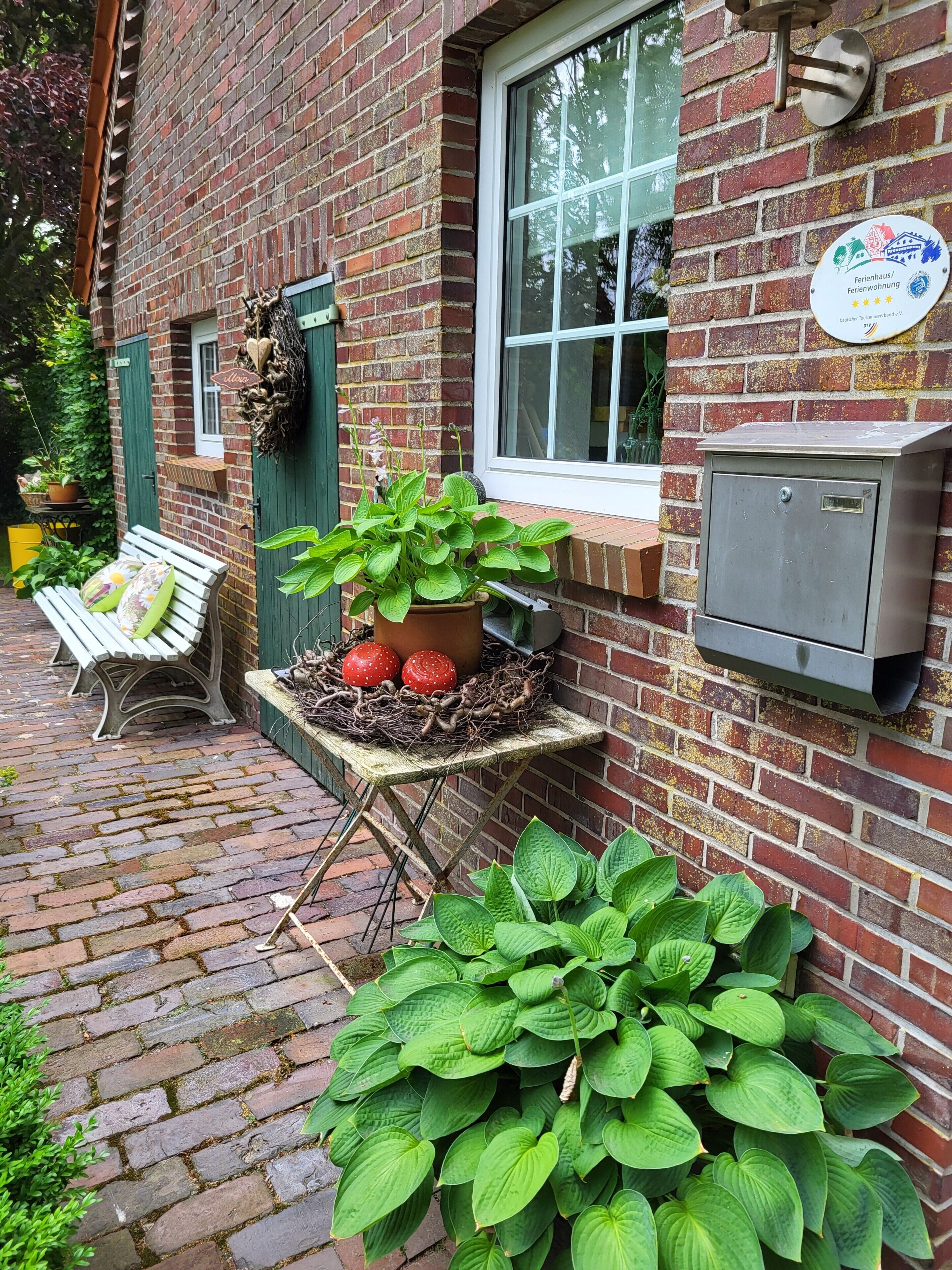 Un bâtiment en briques avec une fenêtre, un banc, une table avec des plantes et une enseigne sur le mur.