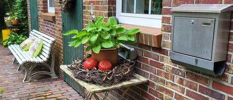Un bâtiment en briques avec une fenêtre, un banc, une table avec des plantes et une enseigne sur le mur.