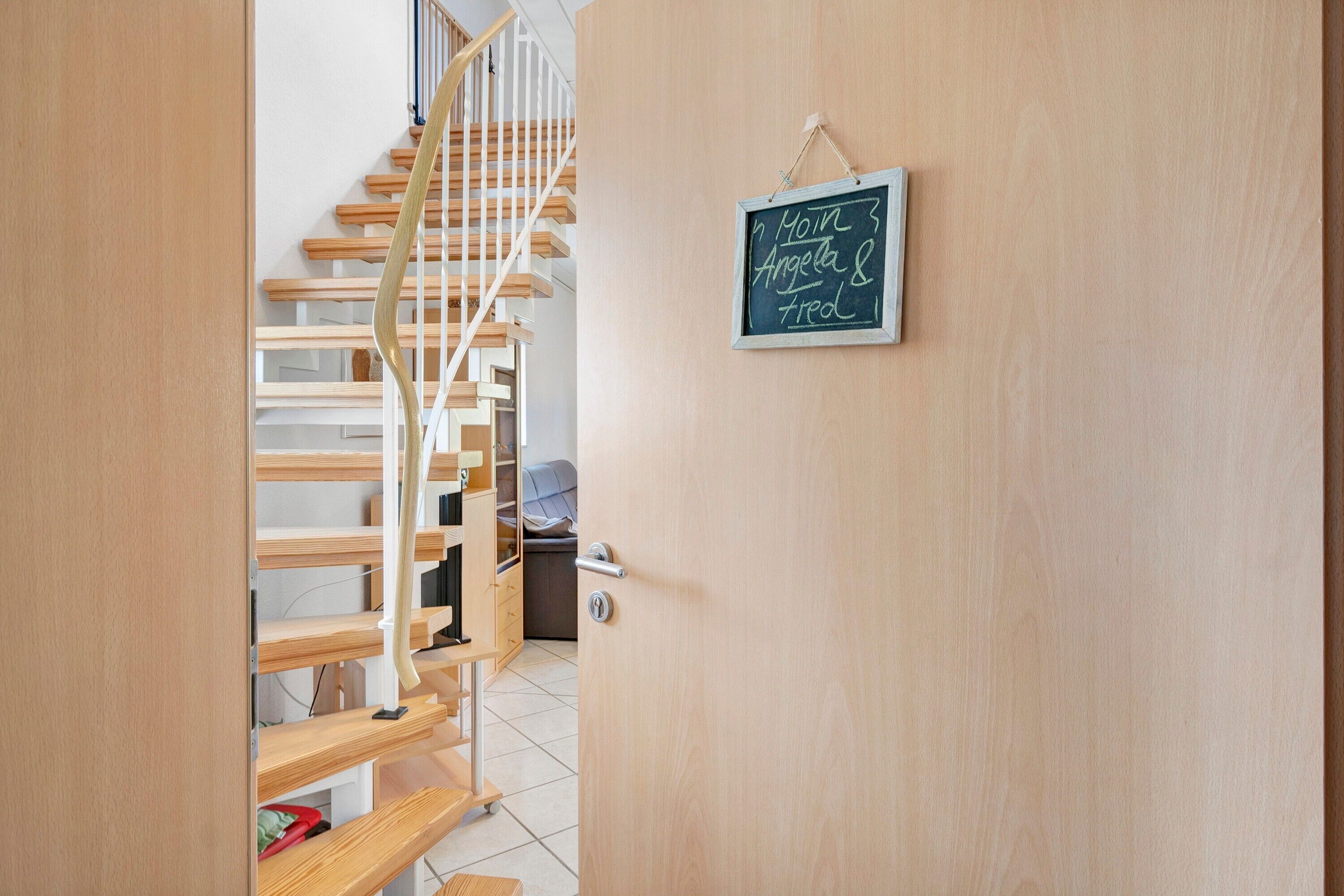 Eine Holztreppe führt zu einem Raum mit einer Tafel, auf der Namen stehen.