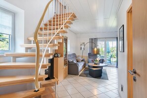 Un intérieur moderne avec un escalier en colimaçon, un canapé, une table basse et un coin repas.
