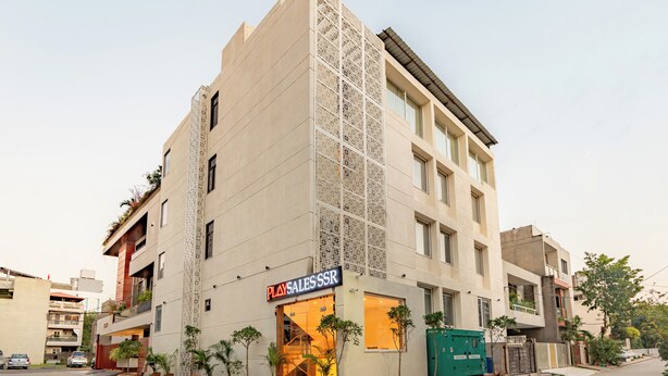 A modern building with a Play Sales & SSK sign, large windows, and potted plants on the ground floor. - Playsales SSR (Indore)