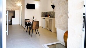 Un espace de vie compact comprenant un coin repas, une cuisine et un mur en pierre.