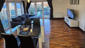 A modern living room with a sofa, dining table, chairs, and a TV. - Tranquil 2 Bed, 2 Bath Apartments walking distance from the Uxbridge town centre (Denham)