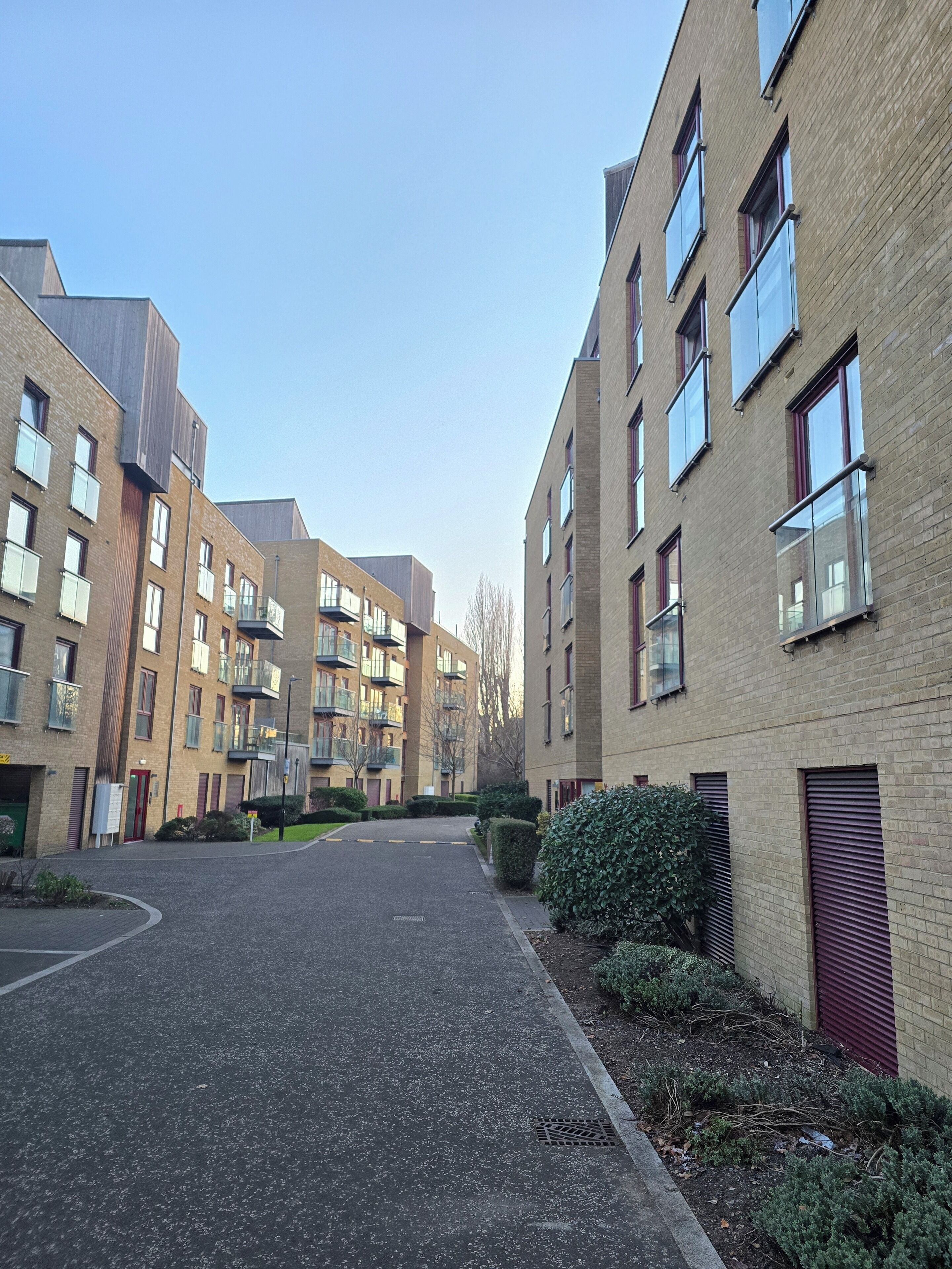A residential building with multiple floors, balconies, and a paved driveway.