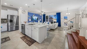Una cocina amplia con armarios blancos, un refrigerador de acero inoxidable y una isla grande con un lavamanos.