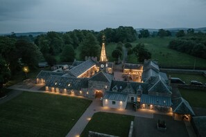 A large stone building with multiple wings, a central tower, and a well-lit courtyard. - Rosebery Estate (Gorebridge)