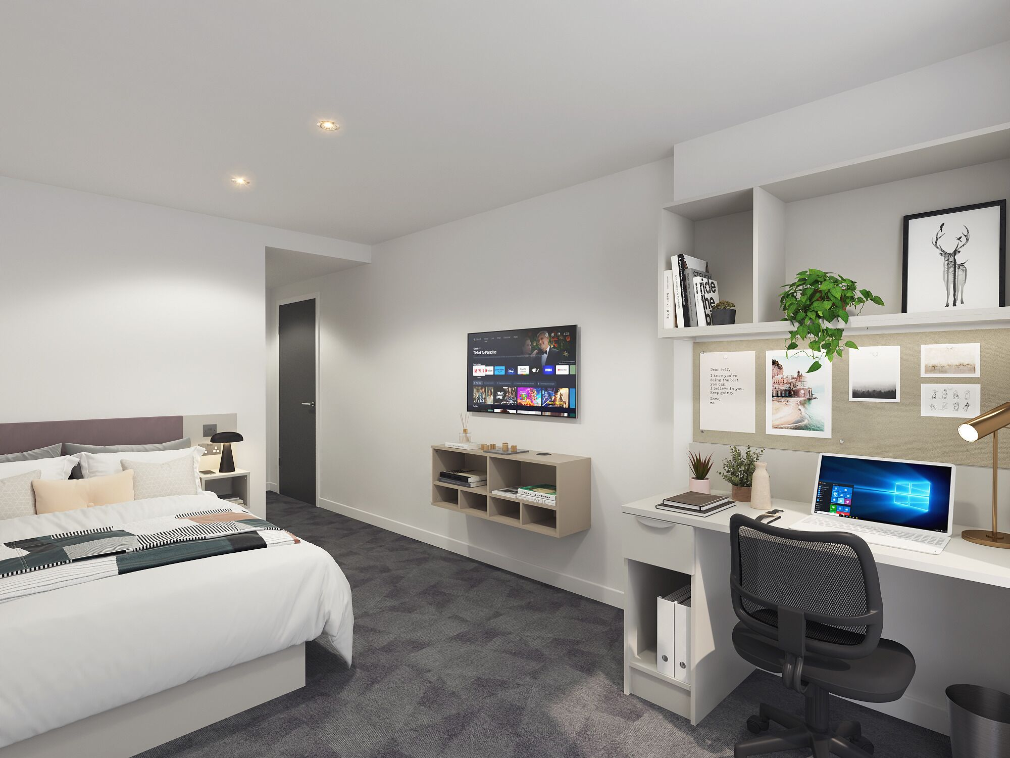 A modern hotel room with a bed, a desk with a laptop, a TV mounted on the wall, and a small plant.