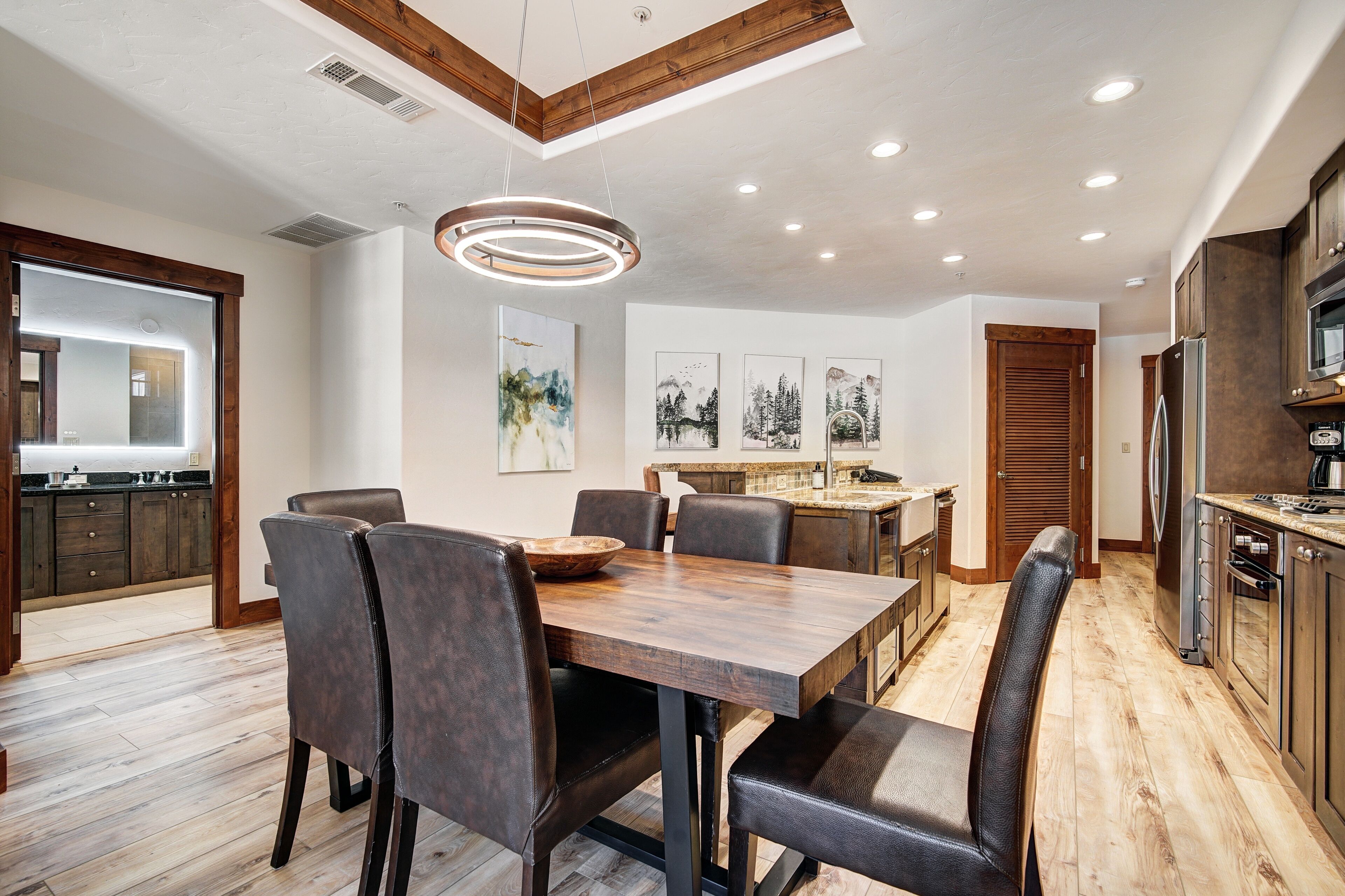 A modern kitchen with wooden cabinets, a central island, and a dining area with a wooden table and chairs.