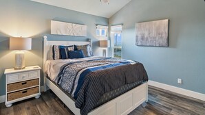 A bedroom with a bed, nightstands, a ceiling fan, and artwork on the walls. - Pier Perfection K101 3 Bedroom Condo (Rockport)