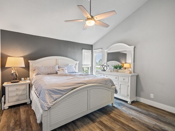 A bedroom with a bed, nightstands, a dresser, a ceiling fan, and a window with blinds. - Pier Perfection K101 3 Bedroom Condo (Rockport)