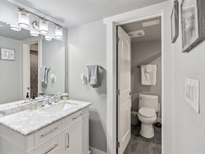 A bathroom with a white vanity, a large mirror, and a toilet. - Pier Perfection K101 3 Bedroom Condo (Rockport)