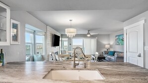A spacious kitchen with a large island, a built-in dishwasher, and a ceiling fan. - Pier Perfection K101 3 Bedroom Condo (Rockport)