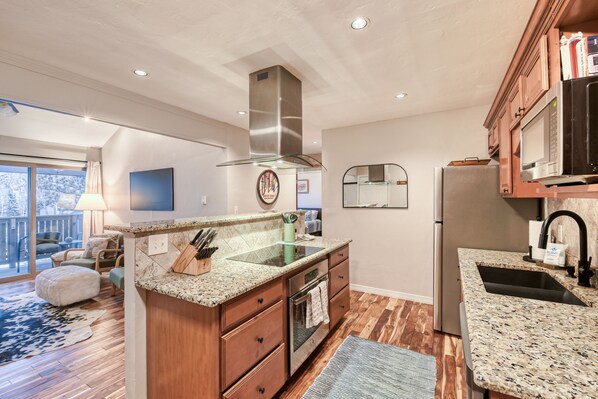 A modern kitchen with granite countertops, stainless steel appliances, and wooden cabinetry. - E309 W Beaver Creek Blvd 2 Bedroom Condo (Avon)