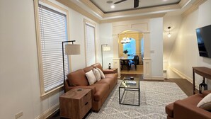 A spacious living room with a brown sectional sofa, a glass coffee table, and a ceiling fan. - Spacious 4-bedroom townhome in fantastic Bronzeville Chicago Neighborhood (Chicago)
