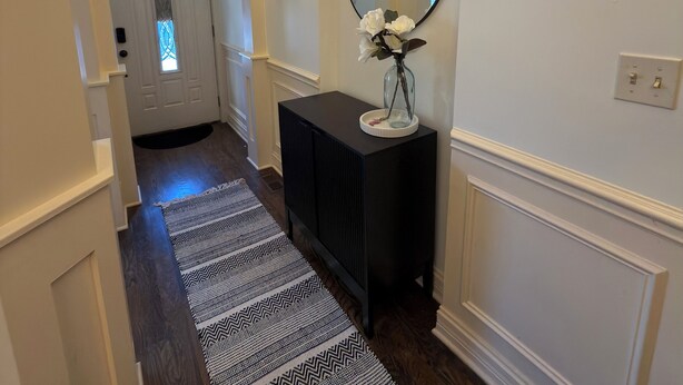 A hallway with a black console table, a mirror, and a patterned rug. - Spacious 4-bedroom townhome in fantastic Bronzeville Chicago Neighborhood (Chicago)