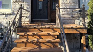 A stone building with a dark wooden door, a welcome sign, and a staircase with wooden railings. - Spacious 4-bedroom townhome in fantastic Bronzeville Chicago Neighborhood (Chicago)