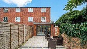 A brick apartment with a patio, a sliding glass door entrance, and a wooden fence.