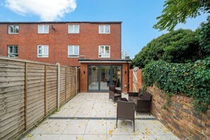Un appartement en briques doté d’un patio, d’une porte-fenêtre coulissante et d’une clôture en bois.