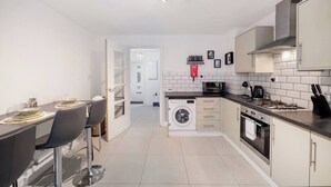 A modern kitchen with a dining area, a washing machine, and a microwave.