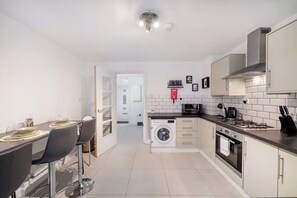 Une cuisine moderne avec un coin repas, un lave-linge et un four à micro-ondes.