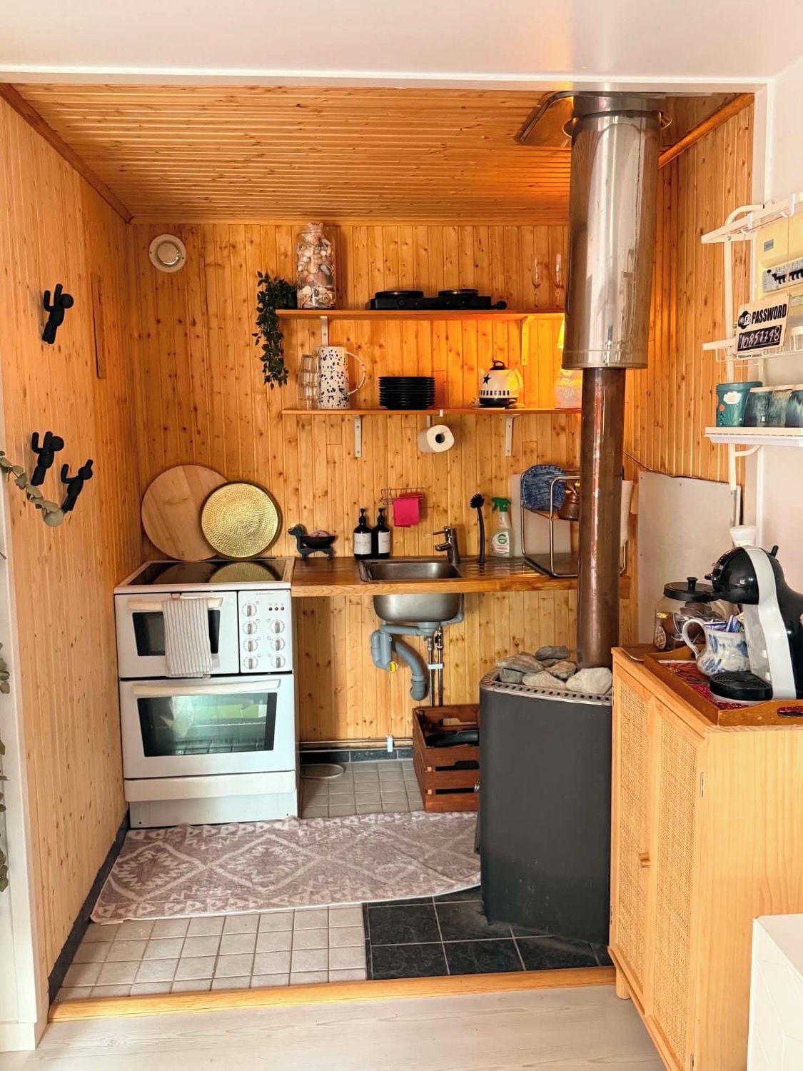 Una cucina compatta con pareti in legno, forno a incasso, lavello e piano cottura.