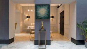 A modern hallway with a marble floor, a central art piece, and two seating areas with chairs and tables. - Private Boutique Hotel in Arcos de la Frontera – Exclusive Use - 4 Suites (Arcos de la Frontera)