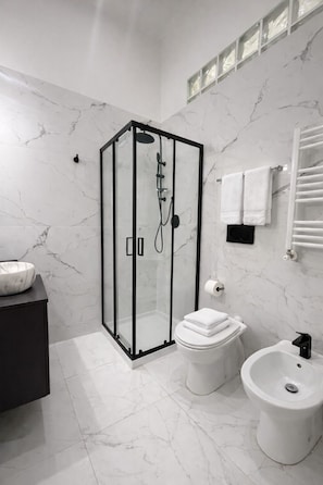 A modern bathroom with a glass-enclosed shower, a toilet, a bidet, and a marble-tiled floor. - San Pietro Vatican Rooms 20 (Rome)