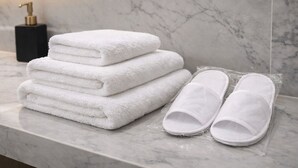 Une pile de serviettes blanches et une paire de chaussons blancs sont posées sur un comptoir en marbre.