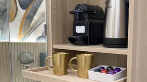 Un coin cuisine équipé d’une machine à café, d’une bouilloire et d’une cafetière, le tout posé sur le plan de travail.