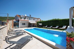 Ein Schwimmbecken mit Liegestühlen und ein Haus mit Balkon.