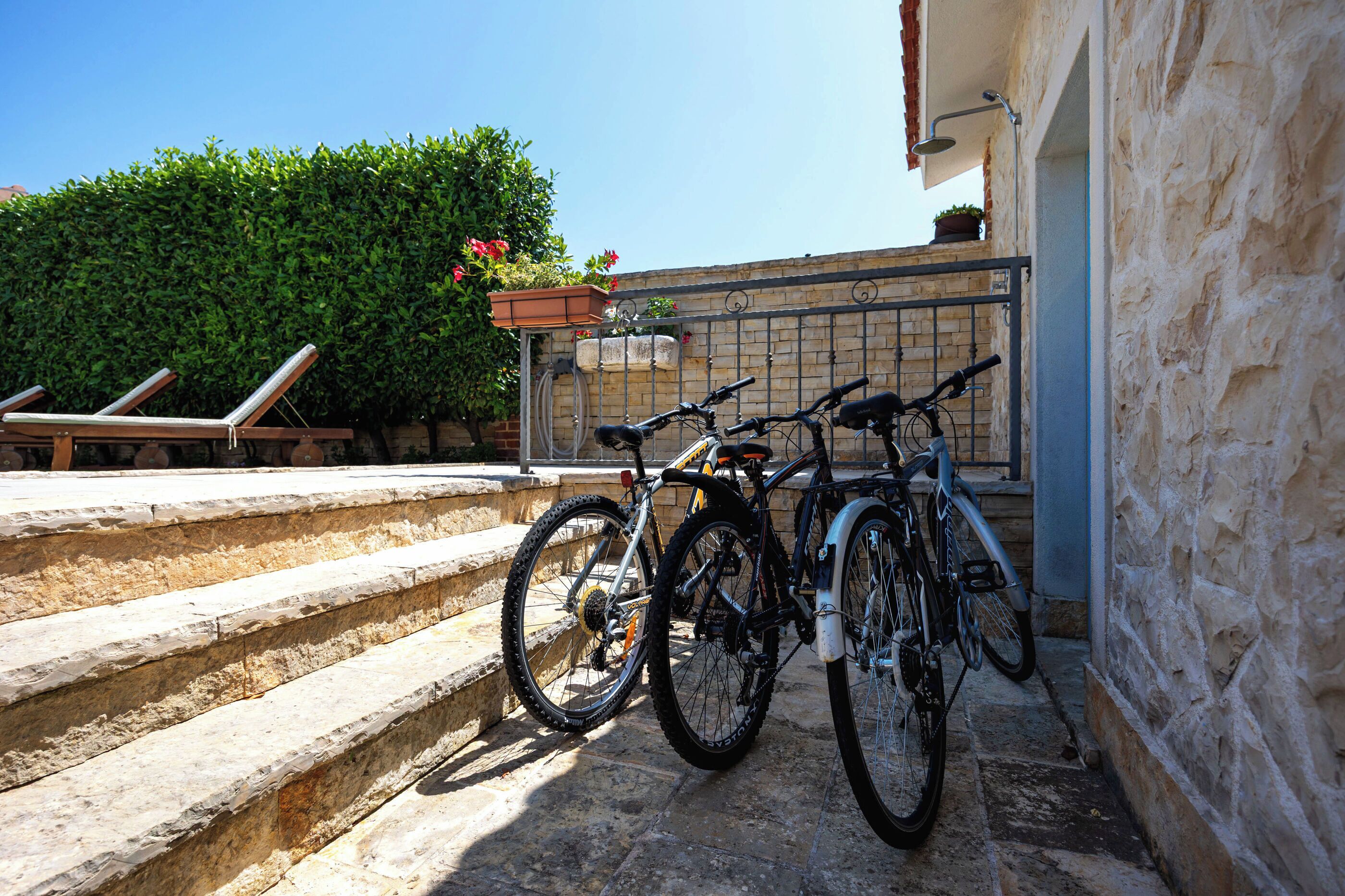 A stone staircase leading to a building with a metal railing. There are two bicycles parked against the railing.