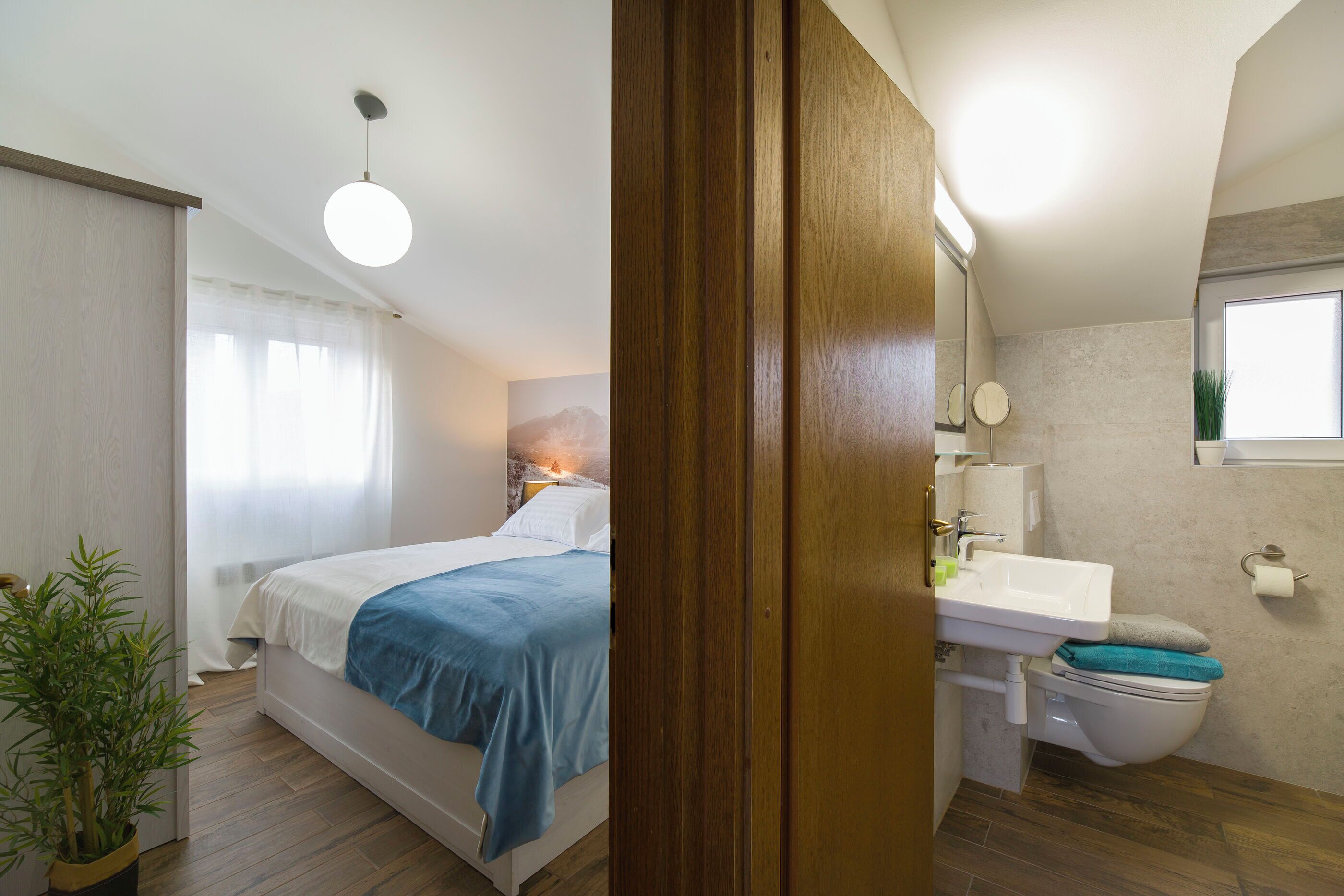 A bedroom with a bed, bedside table, and a hanging light fixture.
