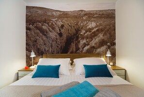 A bedroom with a large bed, two bedside tables with lamps, and a large wall tapestry. - Villa Peaceful Valley With Heated Pool (Sestanovac)