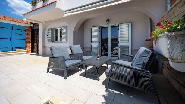Une terrasse extérieure avec des meubles en osier et un sol carrelé.
