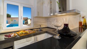 Une cuisine moderne donnant sur une piscine, avec un verre à vin et un plateau de nourriture.