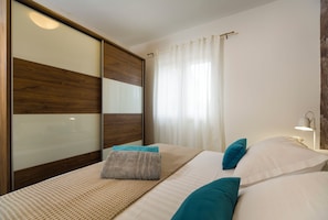A modern bedroom with a large bed, a wooden headboard, and a bedside lamp. - Villa Peaceful Valley With Heated Pool (Sestanovac)