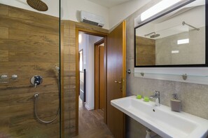 Ein modernes Badezimmer mit einer Duschkabine aus Holz, einer Glasduschtür, einem weißen Waschbecken mit Spiegel und einer eingebauten Heizung.