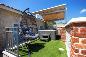 A patio with a hanging chair, a small table, and a covered area. - Villa Peaceful Valley With Heated Pool (Sestanovac)